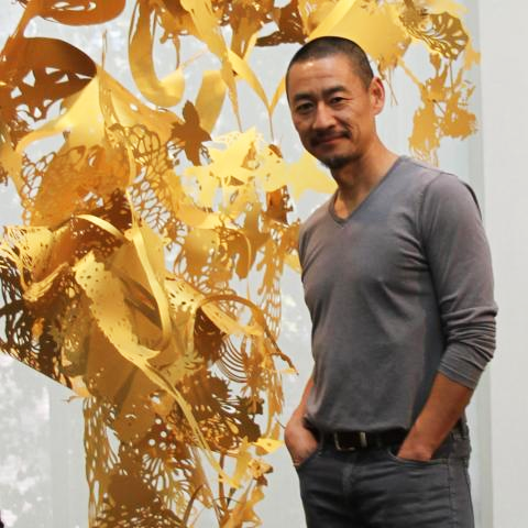 Fred Liang posing in front of one of his golden paper and light pieces.